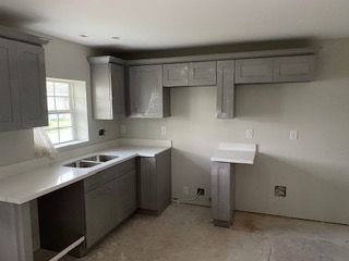 A kitchen with gray cabinets and white counter tops is being remodeled.