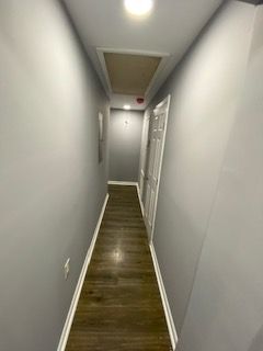 A long hallway with gray walls and wooden floors in a house.