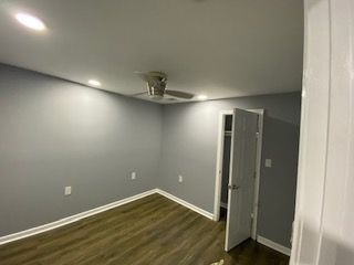 An empty bedroom with a ceiling fan and a closet.