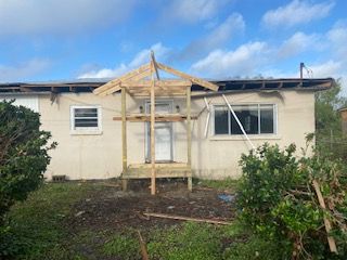 A white house with a wooden porch is being built.