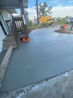 A man is working on a concrete driveway in front of a house.