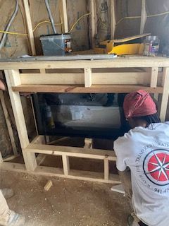 A man is working on a fireplace in a building.