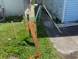 A tripod is sitting in the grass in front of a house.