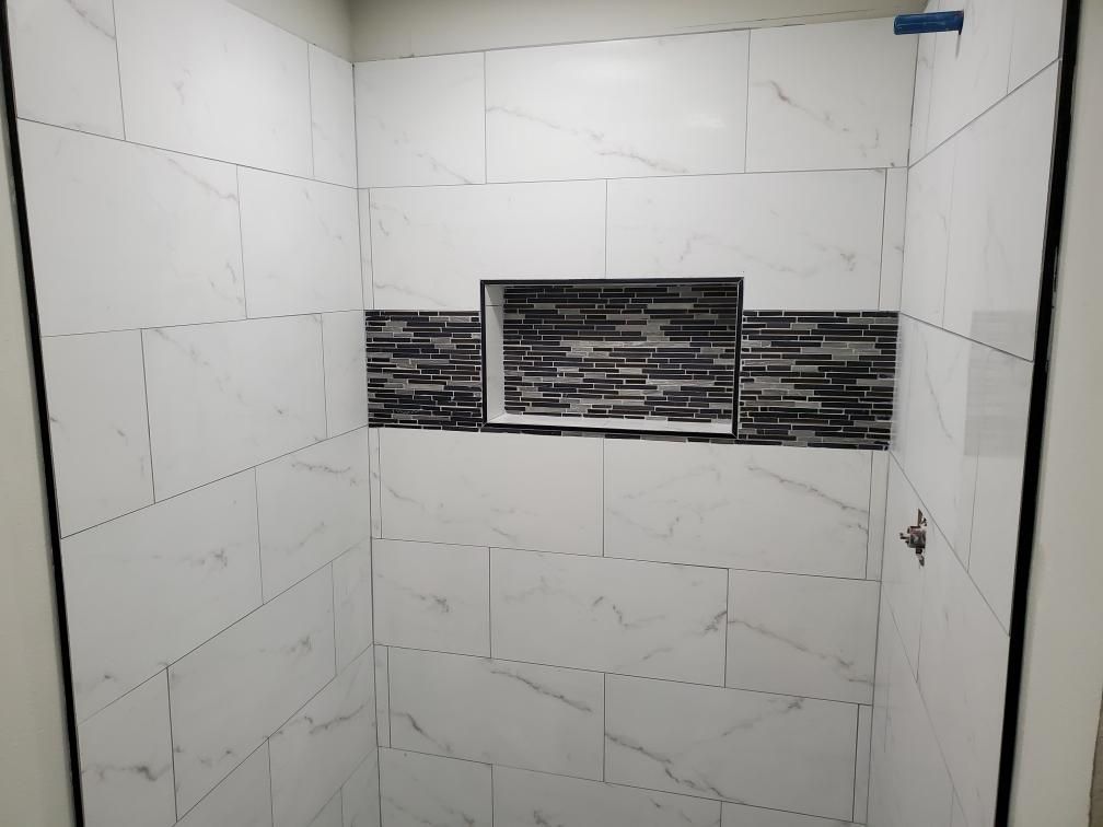 A bathroom with white tiles and a niche in the wall.