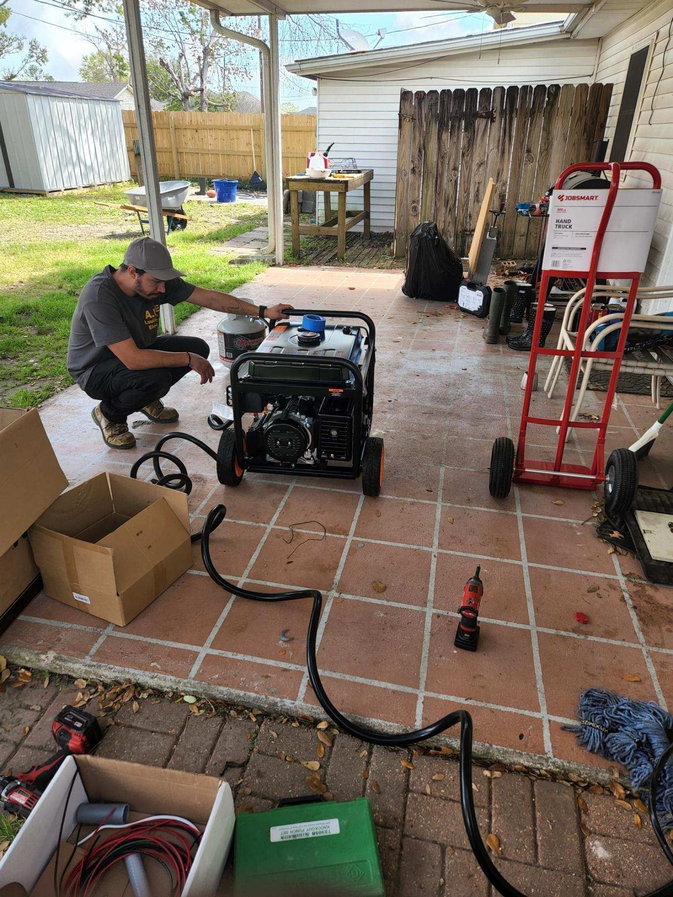 A man is working on a generator on a patio.