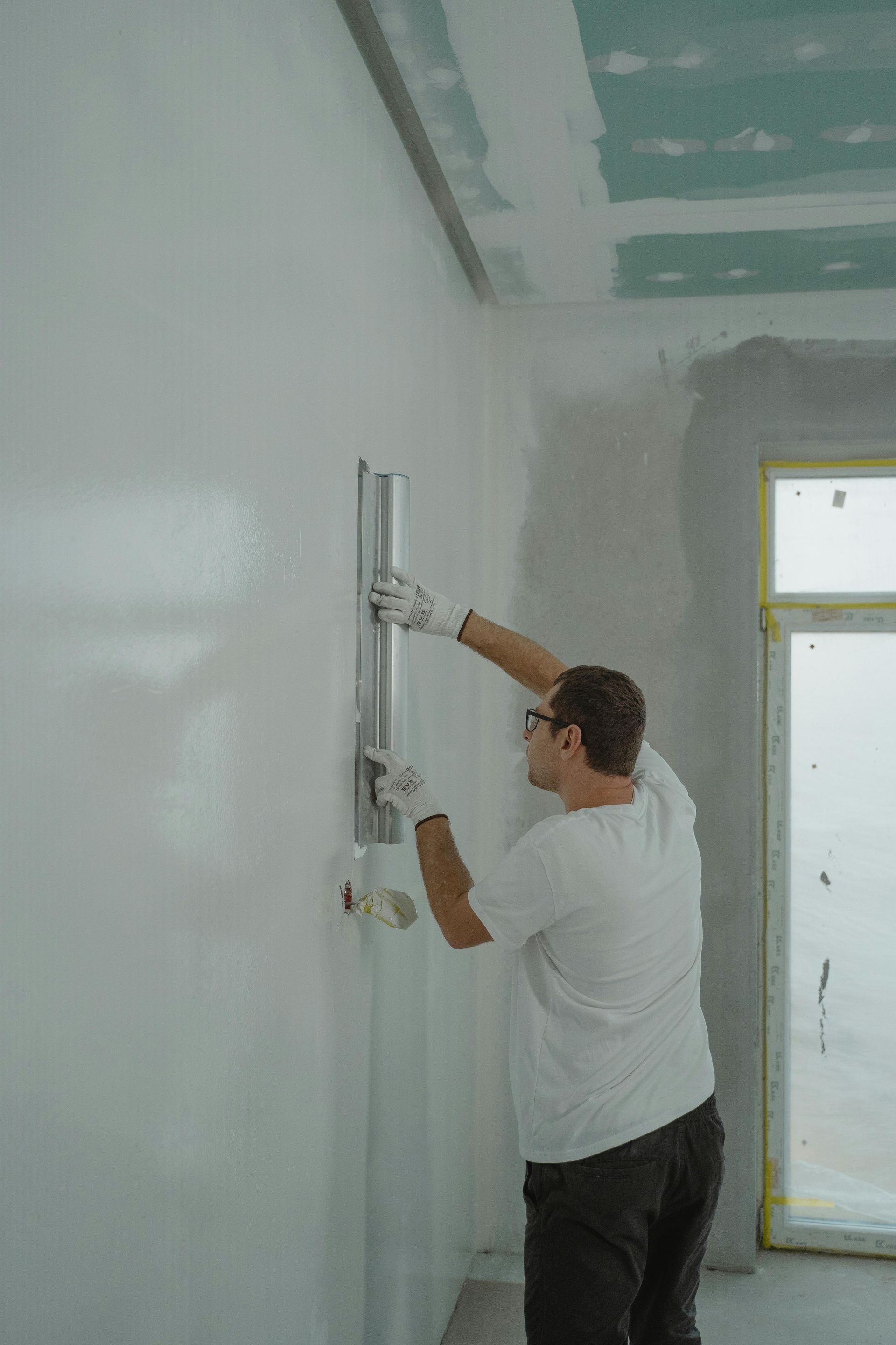 A man is plastering a wall in a room.