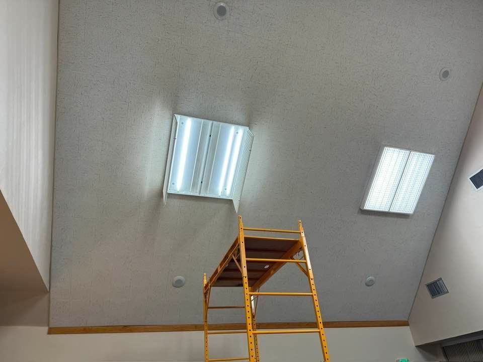 A person is standing on a scaffolding under a ceiling light.