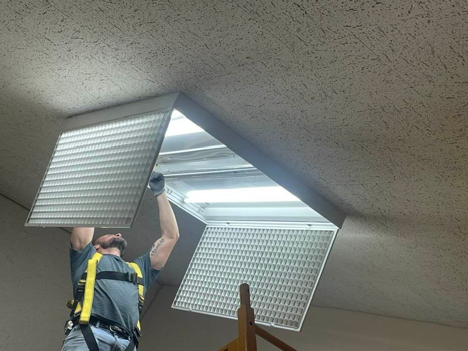 A man is working on a light fixture on the ceiling