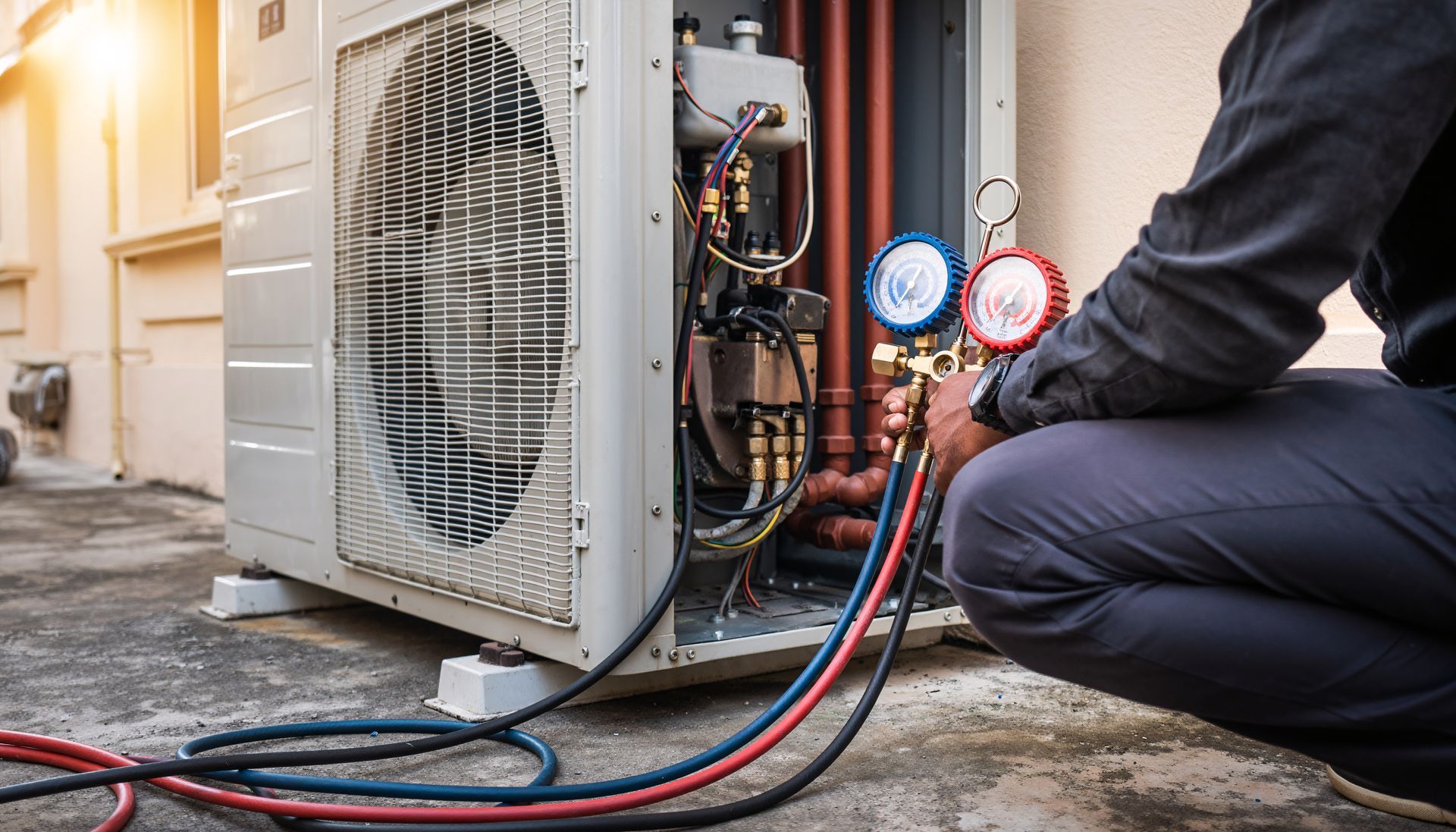 HVAC technician working on an air conditioning unit outside, connecting gauges.