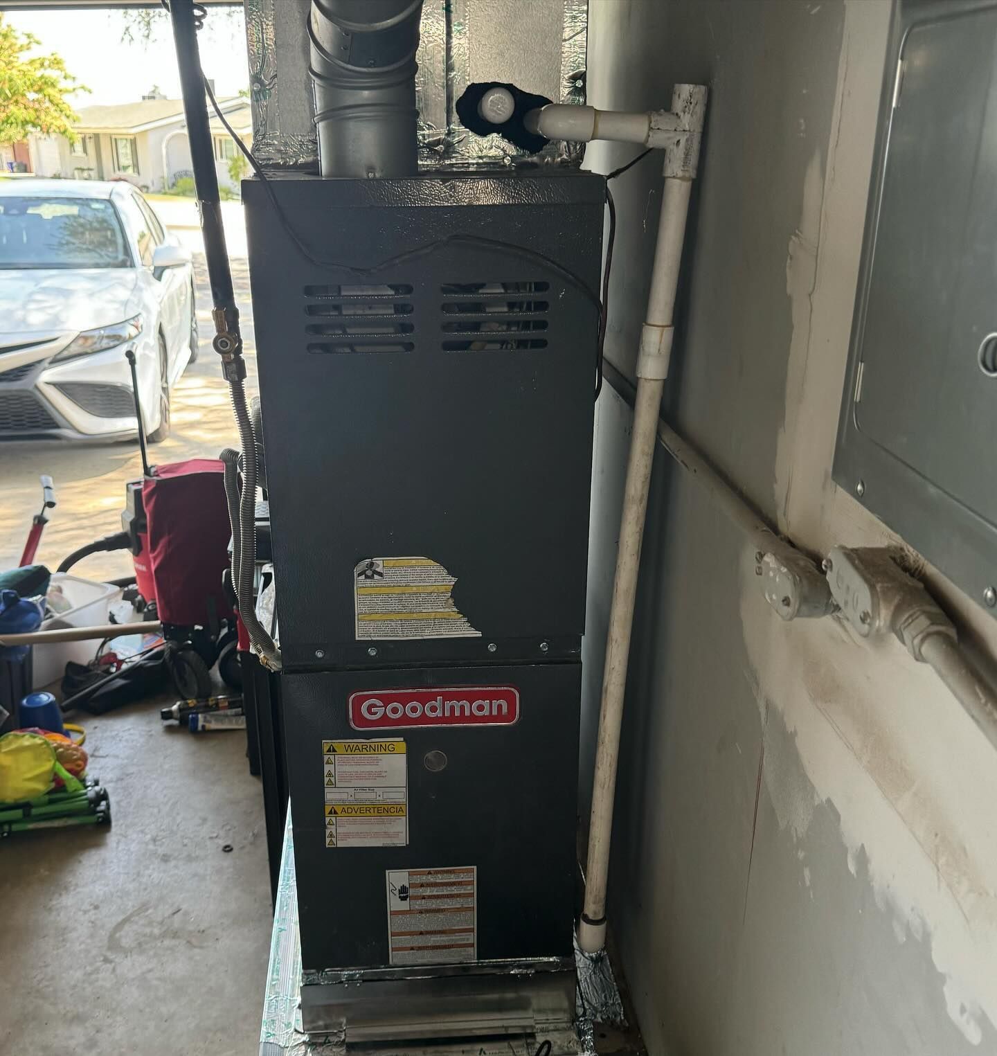 Goodman furnace in a garage setting with a white car in the background.