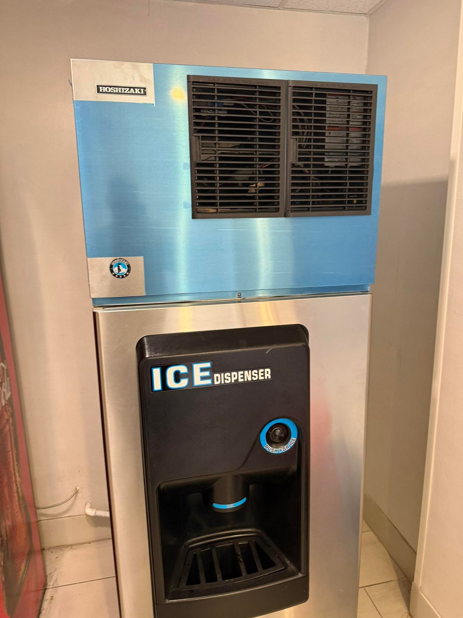 Control panel on stainless steel machine with gauges, buttons, switches, and a red emergency stop button.