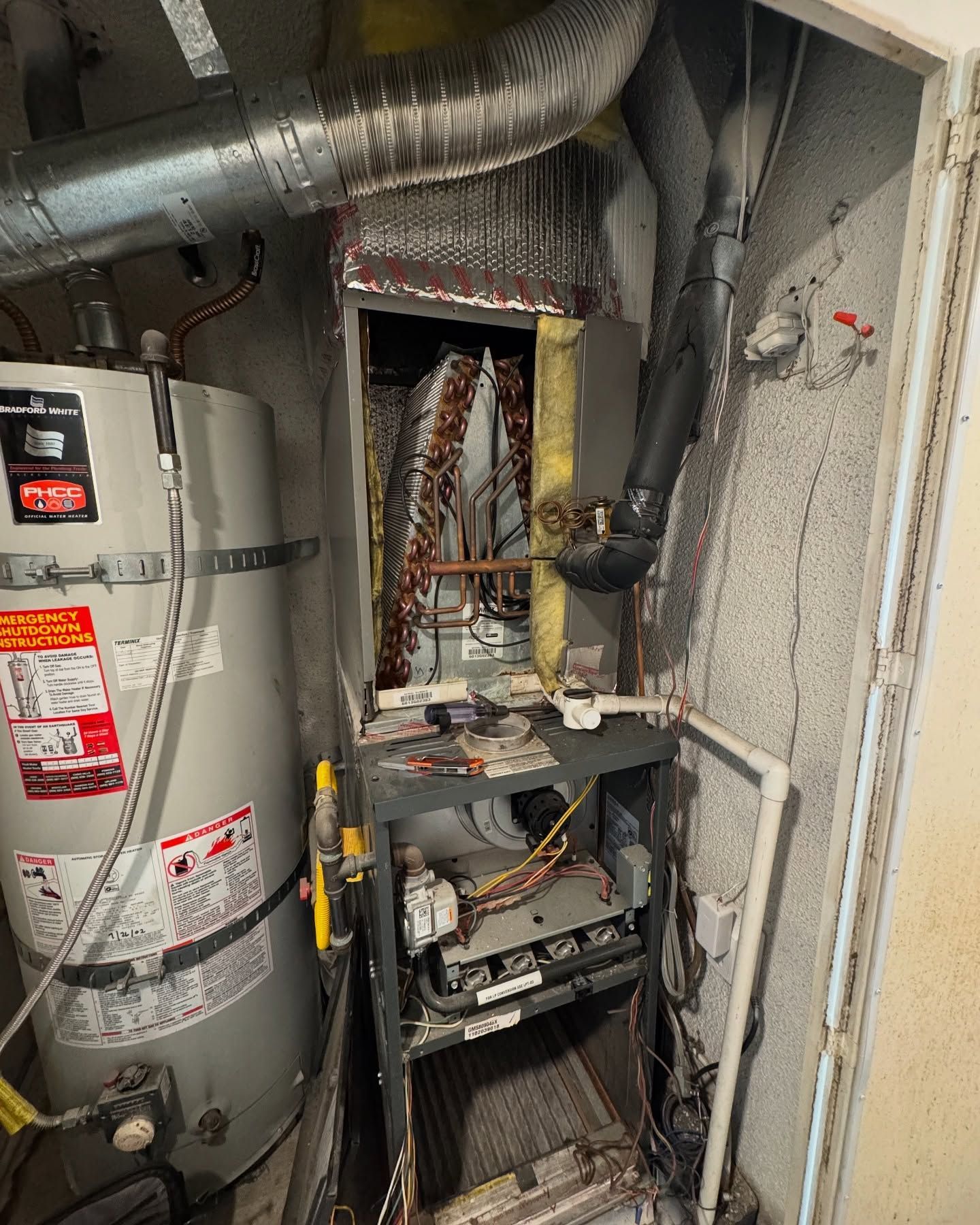 Furnace and water heater in utility room; metal components, ductwork, and exposed wiring.
