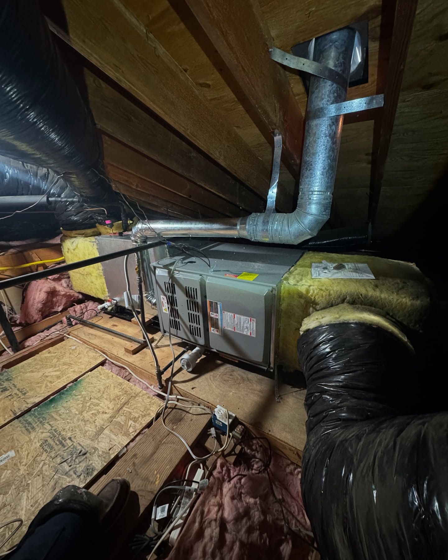 HVAC unit in an attic, with ductwork and insulation.