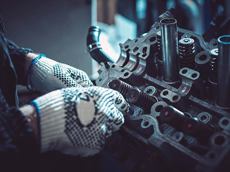 A person wearing gloves is working on a car engine.