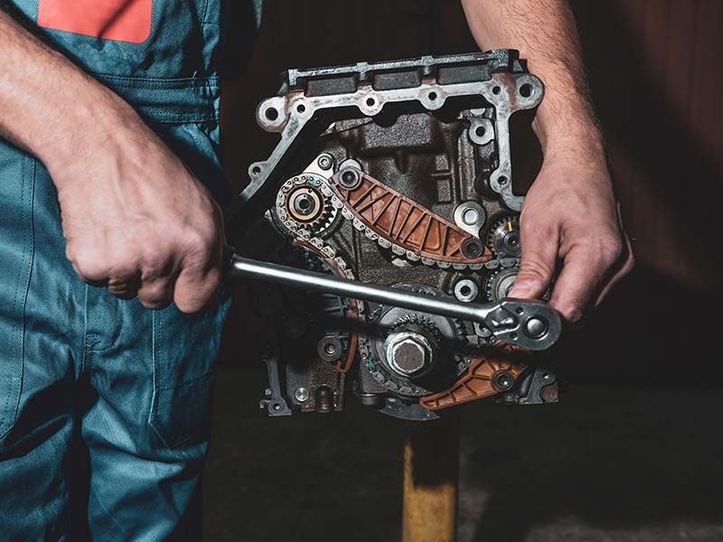 A man is working on a car engine with a wrench.