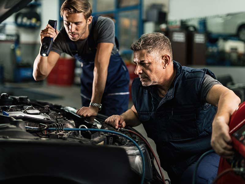 Two men are working on a car in a garage.