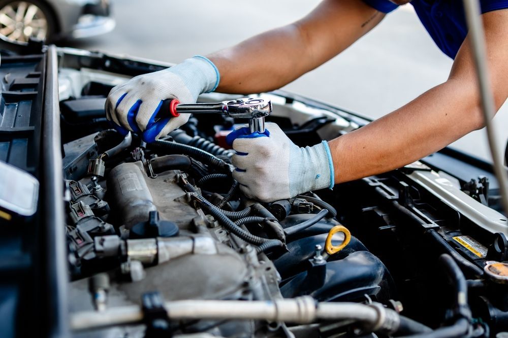 A man is working on the engine of a car.