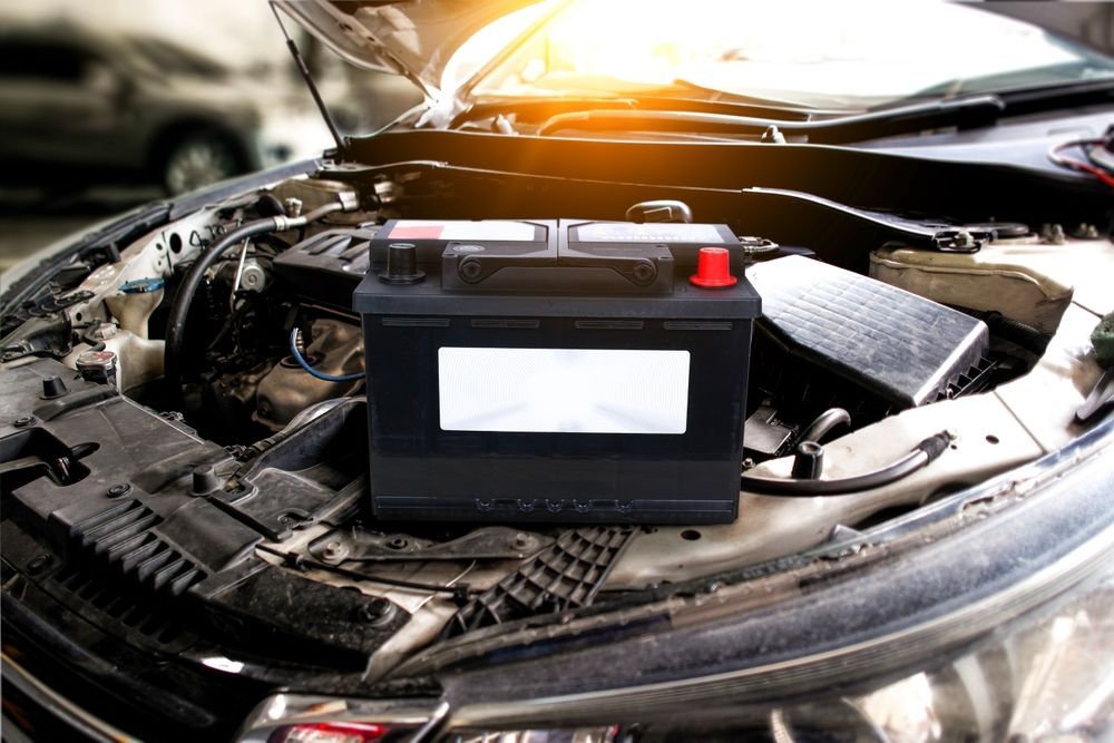 A car with the hood open and a battery in the engine compartment.