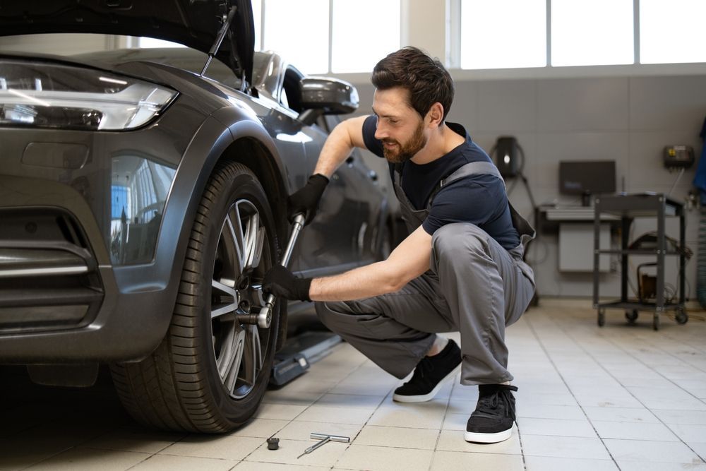 A man is changing a tire on a car in a garage.