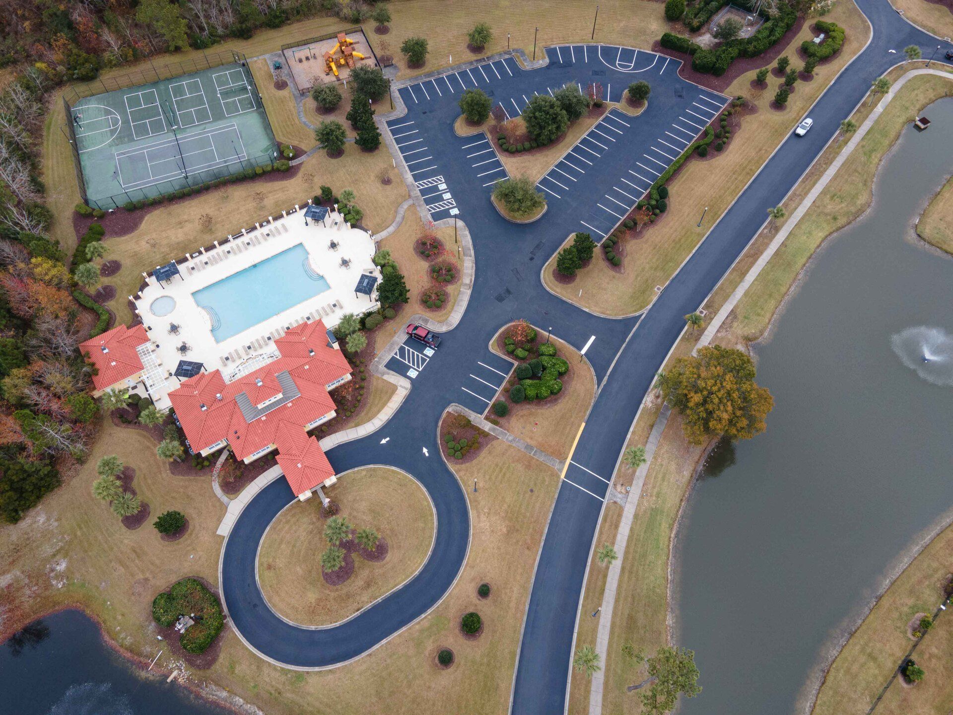 An aerial view of a swimming pool and tennis courts in a residential area.