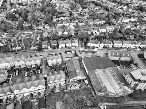 Black and white aerial view of a residential area with houses, trees, and commercial buildings.