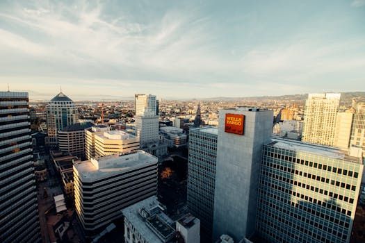 Cityscape view, several tall buildings under a cloudy sky. A Well Fargo sign is visible.