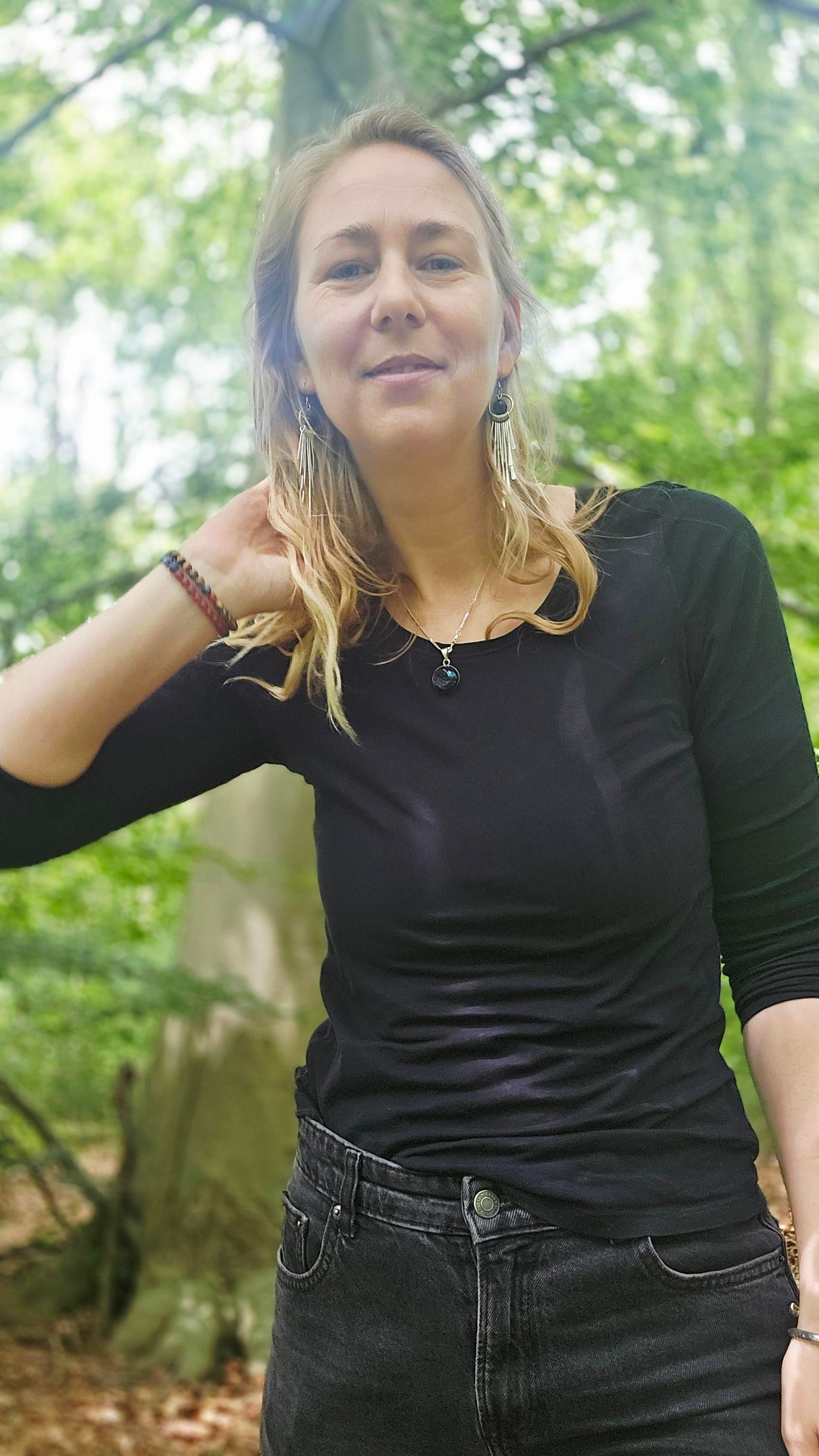 Een vrouw staat op een pier met haar ogen dicht.