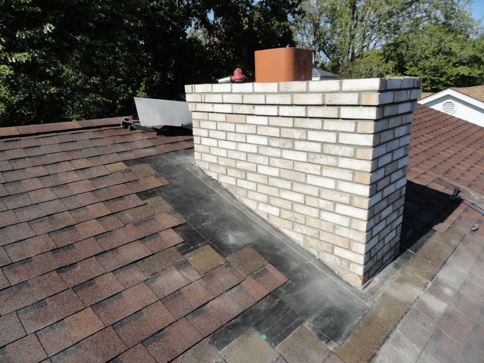 A before photo of a brick chimney on top of a brown roof – Dayton, OH - Miami Valley Chimney