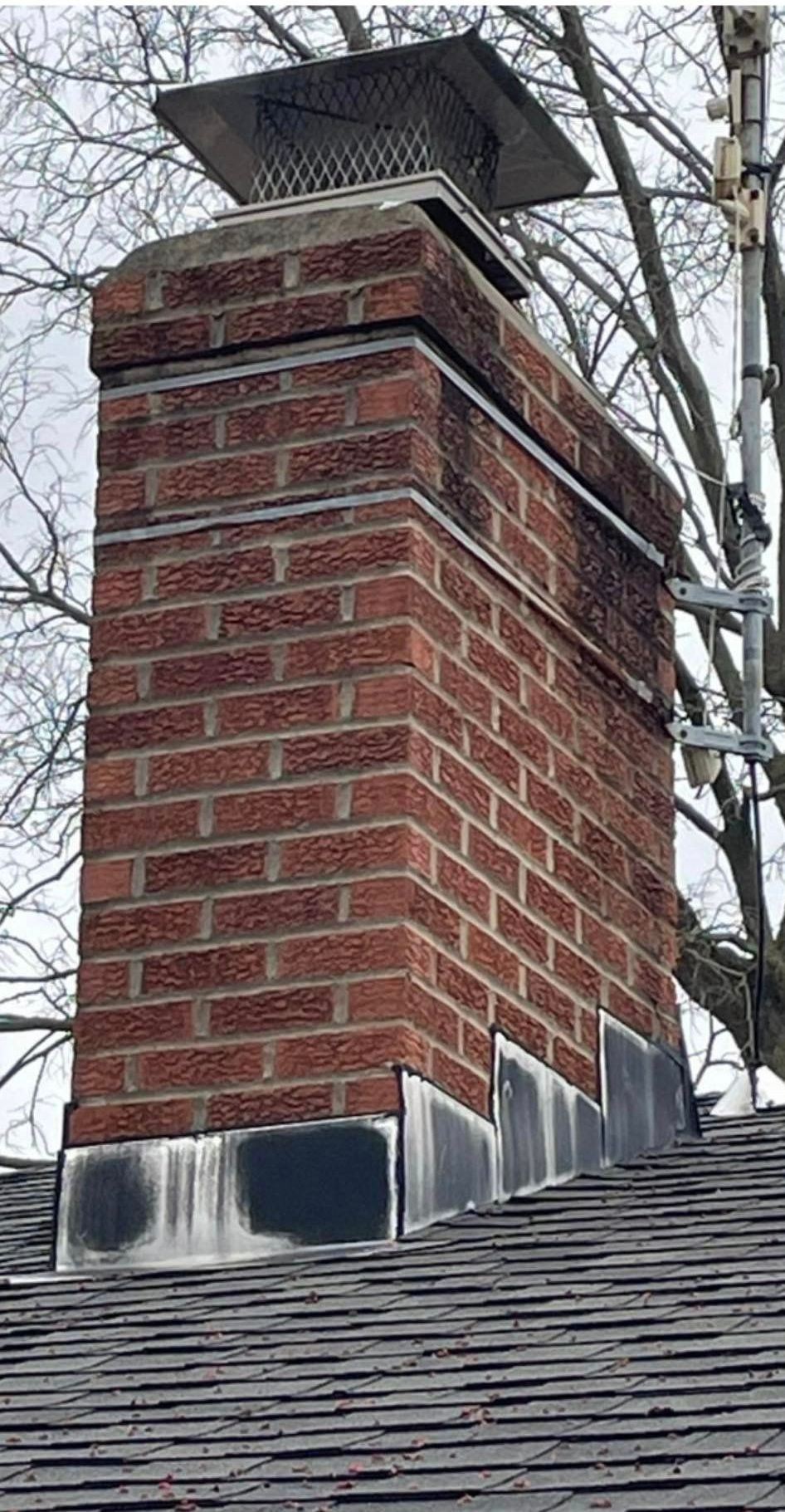 A brick chimney on top of a roof next to a tree – Dayton, OH - Miami Valley Chimney