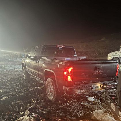 A truck is parked in a muddy field at night.