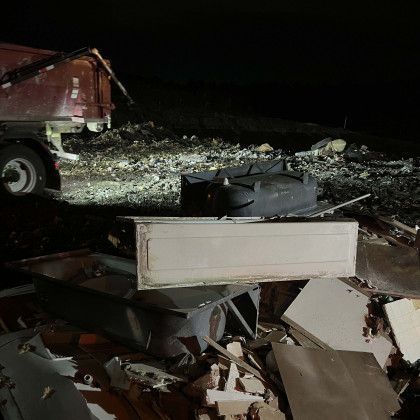 A pile of junk is sitting in front of a dumpster at night