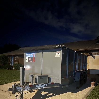 A dumpster is parked in front of a house at night