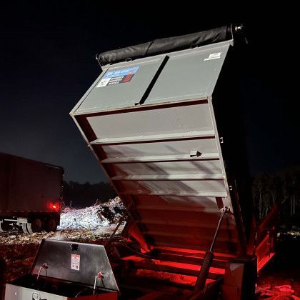 A dumpster is sitting on top of a pile of trash at night.