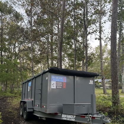 A dumpster trailer is parked in the middle of a forest