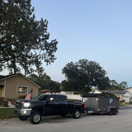 A truck with a trailer attached to it is parked in front of a house