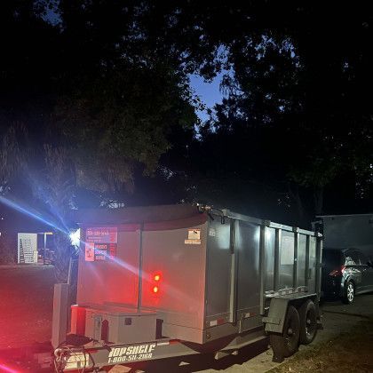 A dumpster trailer is parked in a driveway at night.