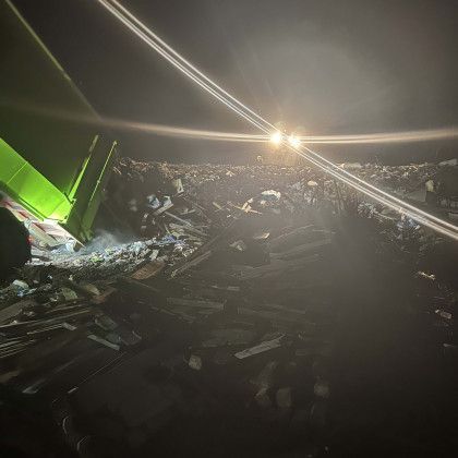 A green truck is driving down a road at night.