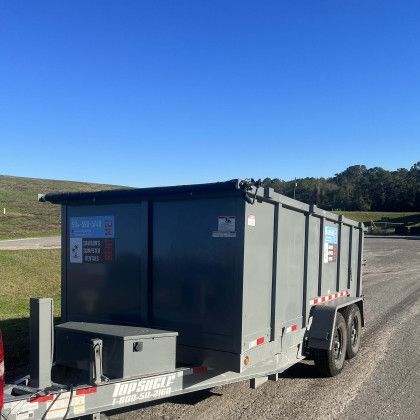 A dumpster trailer is parked on the side of the road.