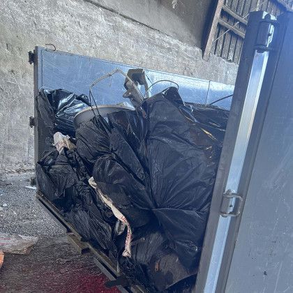 A dumpster filled with lots of black bags