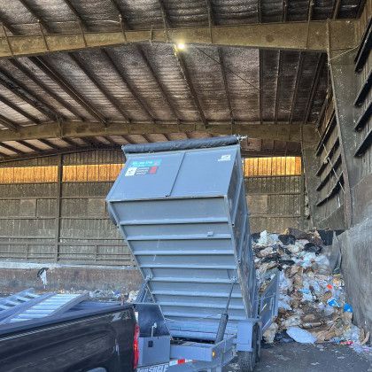 A dumpster is sitting in a warehouse next to a truck.
