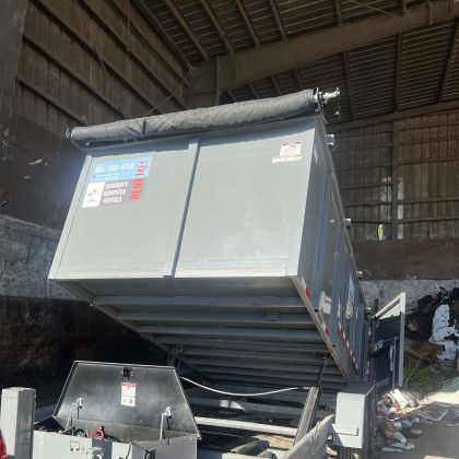 A dumpster is being loaded into a warehouse.