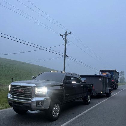 A gmc truck is driving down a road with a trailer attached to it.