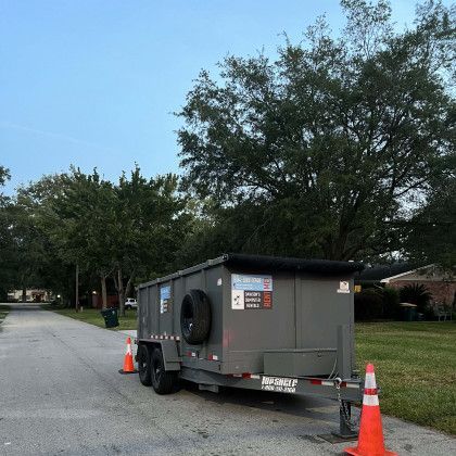 A dumpster is parked on the side of the road