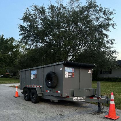 A dumpster on a trailer with a tire on the back