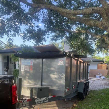 A dumpster trailer is parked in front of a house.