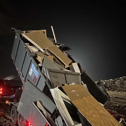 A dumpster is filled with a lot of junk at night