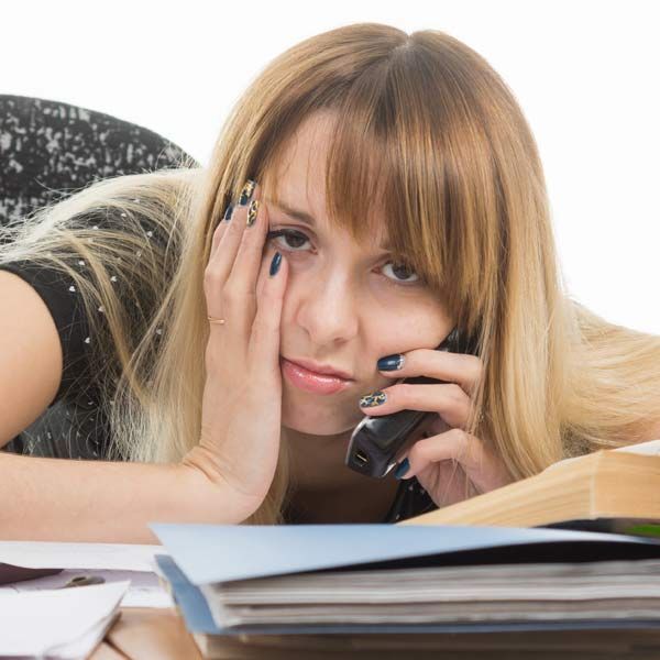 A hung-over woman lying on a desk talking on a cell phone representing Afterparty Recovery IV Therapyy