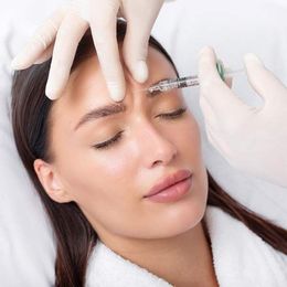 A woman is getting cosmetic treatments such as  a botox injection in her forehead 