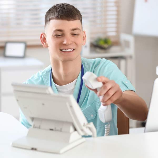 A nurse is sitting at a desk holding a telephone Contacting Victory Medical and Schedule a Private Consultation to Treat Sexual Dysfunction Issues in Men and Women