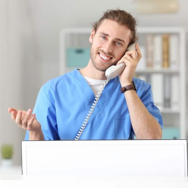 A man in a blue scrub is talking to a patient who is interested in the Hyperbaric Oxygen Chamber Serving Patients in Morris Plains, New Jersey, and Manhattan, New York